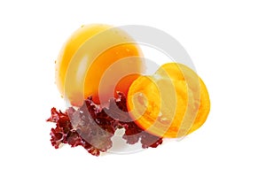 Yellow tomatoe with half slice and salad leaves on white