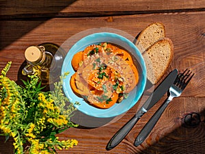 Yellow tomatoes salad with rye bread slices in blue ceramic bowl top view. Ripe fresh colorful vegetables mixed greens