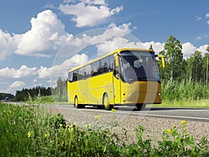 Yellow tourist bus on highway and rural landscape