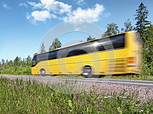Yellow tourist bus on rural highway, motion blur