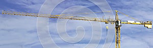 Yellow Tower Crane on Blue Cloudy Skies Background