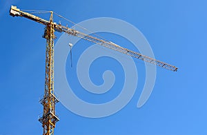 Yellow tower crane while building a house against a blue sky