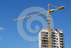 Yellow tower crane at multistory building