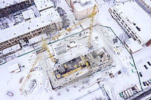 Yellow tower cranes at construction site covered with snow. aerial view