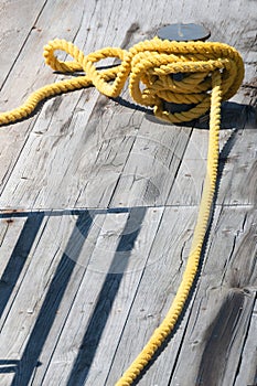 Yellow towing rope wound on a bollard on a pier