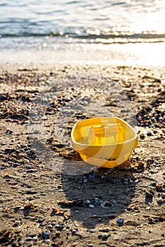 Yellow toy boat on the shores of a forgotten sea