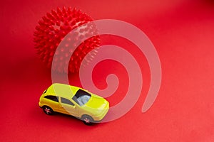 Yellow toy car on red background with coronavirus model, concept idea of taxi and cargo delivery during quarantine