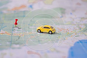 Yellow toy car rides on a topographic map to the destination. Concept travel on avtomibile. The electric car is moving along a