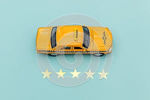 Yellow toy car Taxi Cab and 5 stars rating  on blue background. Smartphone application of taxi service for online