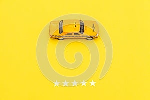 Yellow toy car Taxi Cab and 5 stars rating isolated on yellow background. Smartphone application of taxi service for