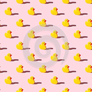 Yellow toy duck sponge or washcloth on pink background - seamless pattern. Trendy beauty bathtime wellness hygiene photography.