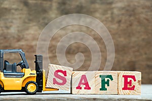 Yellow toy forklift hold letter block S to complete word safe