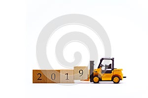 Yellow toy forklift lifting wooden block number 9 to complete word 2019