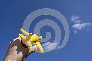 Yellow toy plane flying in to the beautiful blue sky, negative space, concept of going on a magical holiday