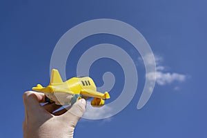 Yellow toy plane flying in to the beautiful blue sky, negative space, concept of going on a magical holiday