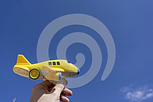 Yellow toy plane flying in to the beautiful blue sky, negative space, concept of going on a magical holiday