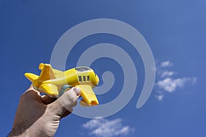 Yellow toy plane flying in to the beautiful blue sky, negative space, concept of going on a magical holiday