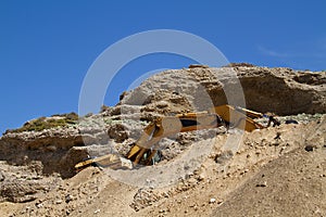 Yellow tracked excavator working in the mountains