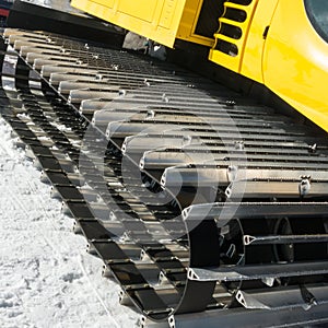 Yellow tracked vehicle on snow, grooming machine