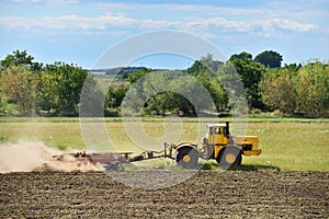 Yellow tractor on land cultivating. Agricultural tractor on cultivation field