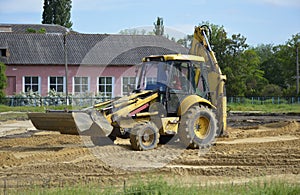 yellow tractor levels the sand at the construction site