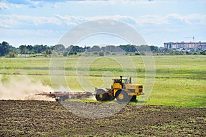 Yellow tractor preparing land for sowing