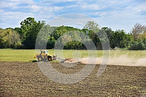 Yellow tractor preparing land for sowing