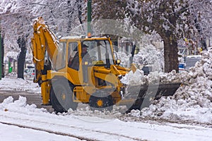 Yellow tractor with snowplow removing snow from the streets