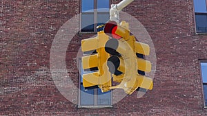 A yellow traffic light hangs at intersection in New York, USA. Red stop signal.