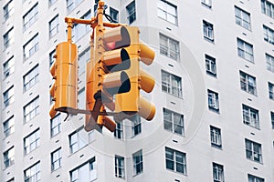 Yellow traffic light showing red light with a grey building on the background