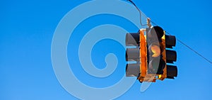 A yellow traffic light with a sky blue background