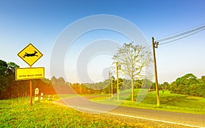 Yellow traffic sign with deer jumping inside the sign and have message `caution wildlife crossing` at the curve asphalt road.