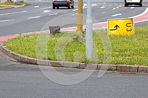 Yellow traffic sign lying down on the grass at a street and signalizes a redirection on European streets to recalculate navigation