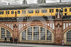 Yellow train on Oberbaum bridge and people walking on the street in city Berlin, Germany