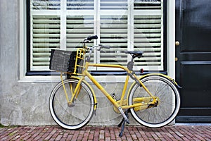 Yellow transport bike parked against renovated house, Amsterdam, Netherlands