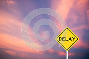 Yellow transportation sign with word delay on violet cloud sky background