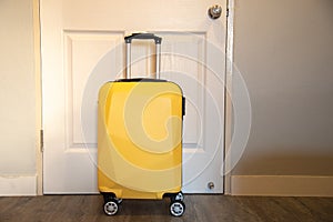 Yellow travel suitcase in the bedroom on the door background - relaxing time, holidays, weekend and traveling concept