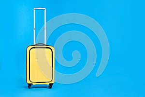 Yellow travel suitcase on light blue background, space for text. Summer vacation