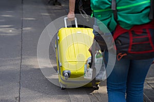 Yellow travel suitcase pulled by man hand on street. Concept of travel