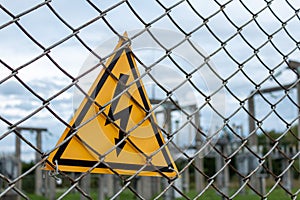 Yellow triangle with lightning behind metal mesh fence