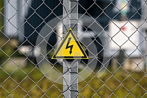 Yellow triangle with lightning on metal fence