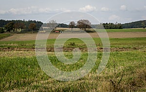 A yellow truck and a tractor with a red trailer running along a small road between the fields