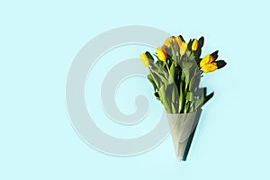 Yellow tulip flowers bouquet with hard shadow on blue background, copy space. Banner for seasonal holiday, springtime concept,