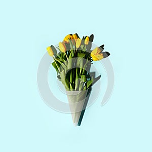 Yellow tulip flowers bouquet with hard shadow on blue background, copy space. Banner for seasonal holiday, springtime concept,