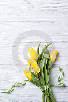 Yellow tulips bouquet on wooden background, top view with copy space