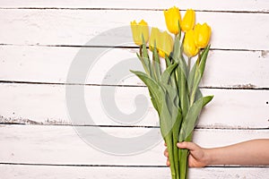 Yellow tulips bunch on white wooden planks rustic barn rural table background. Empty space for lettering, text, letters,