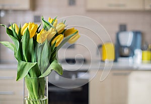 Yellow tulips on kitchen background