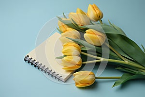 Yellow tulips and a light blue background with a notepad, in the style of understated elegance