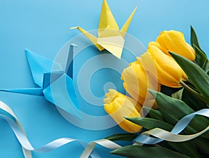 Yellow tulips and origami paper birds on a blue background