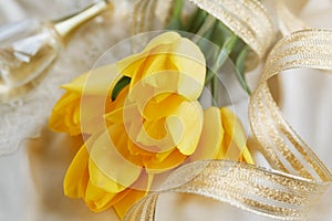 Yellow tulips, perfume and gold ribbon